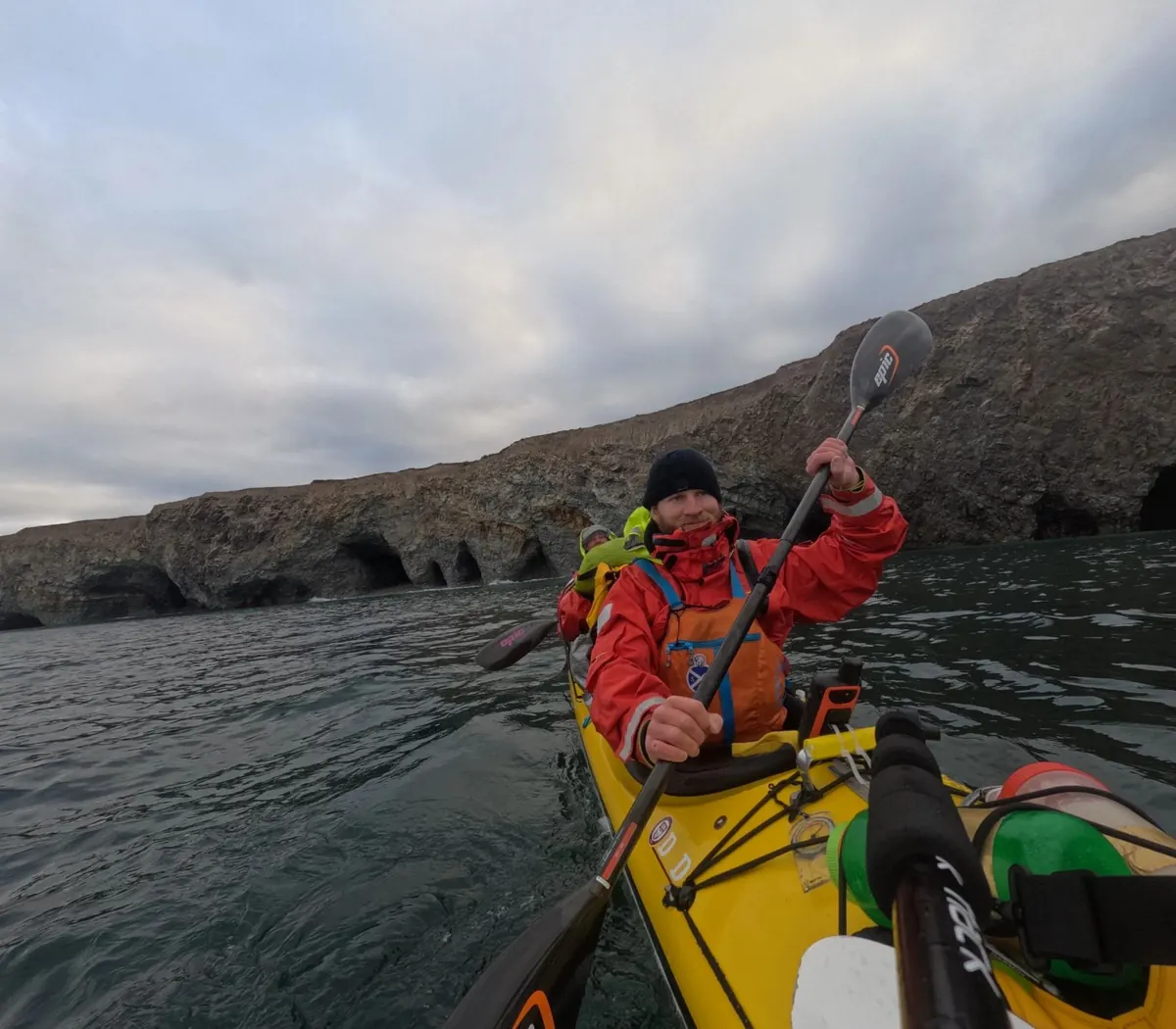 Mark Agnew paddling a loaded expedition sea kayak past Arctic cliffs during the Northwest Passage crossing